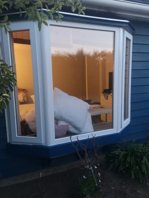 Ventana de PVC blanca tipo bow window en casa de madera