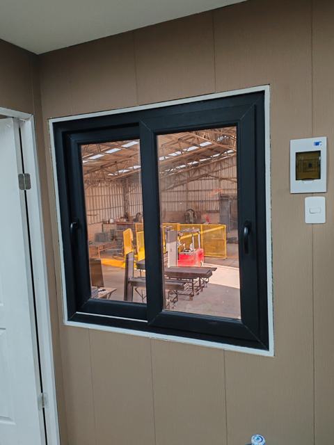 Ventana corredera de PVC negra en oficina de fábrica